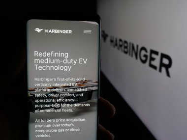Stuttgart, Almanya - 12-03-2025: ABD 'li otomotiv şirketi Harbinger Motors Inc.' in web sayfası ile akıllı telefon sahibi kişi logonun önünde ekranda. Telefon ekranının merkezine odaklan.