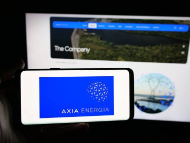 Stuttgart, Almanya - 12-03-2025: İnternet sitesi önünde üzerinde enerji şirketi Axia Energia 'nın logosu olan akıllı telefonu tutan kişi. Telefon ekranına odaklan.