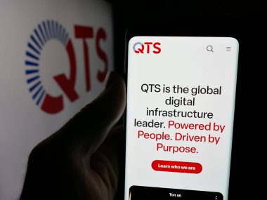 Stuttgart, Almanya - 12-05-2025: ABD 'li veri merkezi şirketi QTS Emlak Güven LLC' nin web sayfası olan cep telefonu logosu önünde ekranda. Telefon ekranının merkezine odaklan.