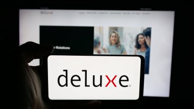 Stuttgart, Almanya - 12-08-2025: ABD 'li finans şirketi Deluxe Corporation' ın logosunun bulunduğu cep telefonu web sayfası önünde ekranda. Telefon ekranına odaklan.