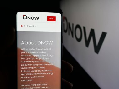 Stuttgart, Almanya - 12-08-2025: ABD 'li enerji çözümleri şirketi Dnow Inc.' nin web sayfası ile cep telefonu tutan kişi logonun önünde ekranda. Telefon ekranının merkezine odaklan.