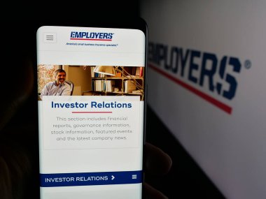 Stuttgart, Almanya - 12-10-2025: ABD 'li sigorta şirketi İşverenler Holding Inc.' nin internet sayfası ile cep telefonu tutan kişi logonun önünde ekranda. Telefon ekranının merkezine odaklan.