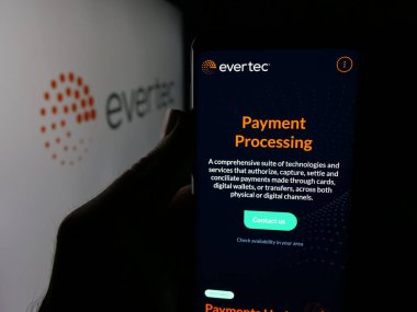 Stuttgart, Almanya - 12-10-2025: Finans teknoloji şirketi Evertec Inc. 'in web sayfası ile akıllı telefonu olan kişi logonun önünde ekranda. Telefon ekranının merkezine odaklan.