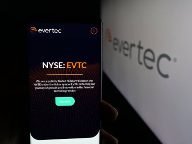 Stuttgart, Almanya - 12-10-2025: Finansal teknoloji şirketi Evertec Inc. 'in web sayfası olan cep telefonu logonun önünde ekranda. Telefon ekranının merkezine odaklan.