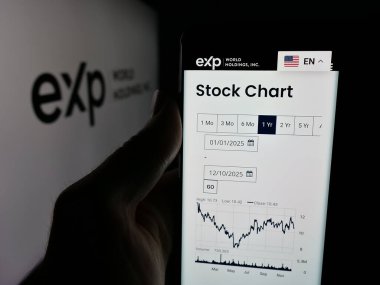 Stuttgart, Almanya - 12-10-2025: Emlak şirketi eXp World Holding Inc. 'nin web sayfası ile akıllı telefonu olan kişi logonun önünde ekranda. Telefon ekranının merkezine odaklan.