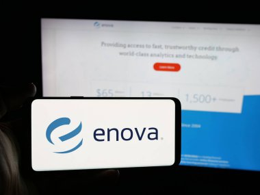 Stuttgart, Almanya - 12-10-2025: ABD 'li finans şirketi Enova International Inc.' in logosunu elinde tutan kişi web sitesinin önünde ekranda. Telefon ekranına odaklan.