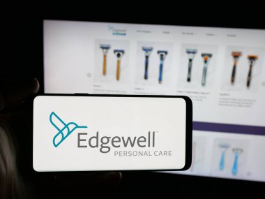 Stuttgart, Almanya - 12-10-2025: ABD 'li iş adamı Edgewell Personal Care Company' nin logosunu elinde tutan kişi web sitesinin önünde ekranda. Telefon ekranına odaklan.
