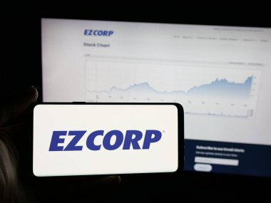 Stuttgart, Almanya - 12-11-2025: ABD 'li rehin dükkanı şirketi EZCORP Inc.' in logosunu elinde tutan kişi web sitesinin önünde ekranda. Telefon ekranına odaklan.