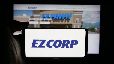 Stuttgart, Almanya - 12-11-2025: Web sayfası önünde ekranda ABD 'li rehin dükkanı şirketi EZCORP Inc.' in logosunun bulunduğu cep telefonu sahibi kişi. Telefon ekranına odaklan.