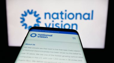 Stuttgart, Almanya - 12-11-2025: Optik perakende şirketi National Vision Inc. 'in web sitesi ile birlikte cep telefonu logonun önünde ekranda. Telefon ekranının sol üst kısmına odaklan.