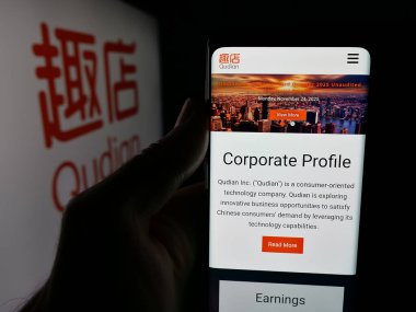 Stuttgart, Almanya - 12-12-2025: Çinli teknoloji şirketi Qudian Inc. 'in web sayfası ile akıllı telefonu olan kişi logonun önünde ekranda. Telefon ekranının merkezine odaklan.
