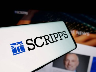 Stuttgart, Almanya - 12-12-2025: Yayın şirketi The E.W. 'nin logosuna sahip akıllı telefon Scripps Company web sitesinin önünde ekranda. Telefon ekranının merkez soluna odaklan.