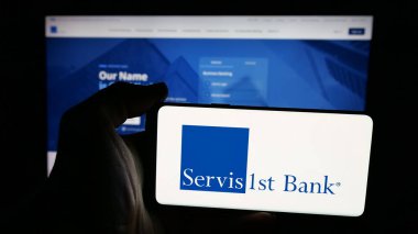 Stuttgart, Almanya - 12-12-2025: Web sayfasının önünde ekranda ABD Bankası ServisFirst Bancshare Inc. logosu olan cep telefonu sahibi kişi. Telefon ekranına odaklan.