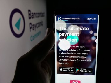 Stuttgart, Almanya - 12-16-2025: Belçikalı Bancontact Payconiq Company 'nin web sayfası ile logo önünde cep telefonu tutan kişi. Telefon ekranının merkezine odaklan.