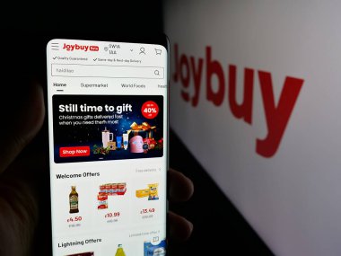 Stuttgart, Almanya - 12-17-2025: Logo önündeki ekranda e-ticaret şirketi Joybuy 'ın (Joybuy.com) web sayfası ile akıllı telefon tutan kişi. Telefon ekranının merkezine odaklan.