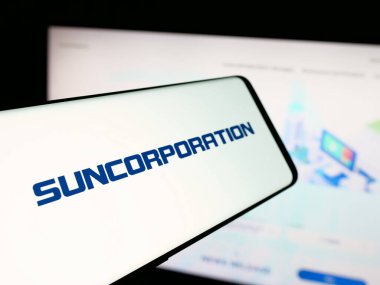 Stuttgart, Almanya - 12-17-2025: Japon elektronik şirketi Sun Corporation 'ın logosunu içeren akıllı telefon web sitesinin önünde ekranda. Telefon ekranının merkez soluna odaklan.