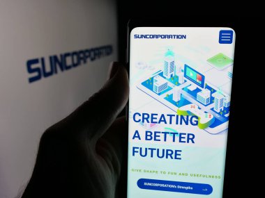 Stuttgart, Almanya - 12-17-2025: Japon elektronik şirketi Sun Corporation 'ın web sayfası olan akıllı telefon sahibi kişi logonun önünde ekranda. Telefon ekranının merkezine odaklan.