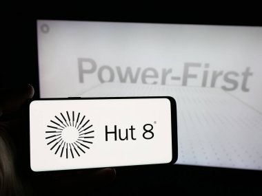 Stuttgart, Almanya - 12-17-2025: ABD kripto şirketi Hut 8 Corp 'un logosuna sahip akıllı telefon sahibi kişi web sitesinin önünde ekranda. Telefon ekranına odaklan.