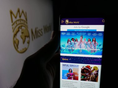 Stuttgart, Almanya - 12-18-2025: Güzellik yarışması organizasyonu Miss World 'ün internet sayfası olan akıllı telefonu logonun önünde tutan kişi. Telefon ekranının merkezine odaklan.