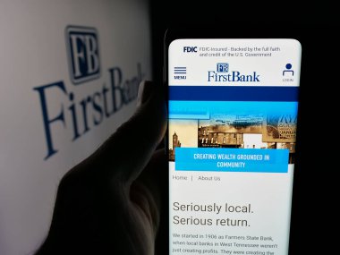 Stuttgart, Almanya - 12-18-2025: ABD 'li FB Financial Corp (FirstBank) şirketinin web sayfası logonun önünde duran kişi. Telefon ekranının merkezine odaklan.