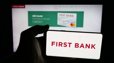 Stuttgart, Almanya - 12-18-2025: Finans şirketi First Bank 'ın (LocalFirstBank) logosuna sahip cep telefonu web sayfası önünde ekranda. Telefon ekranına odaklan.
