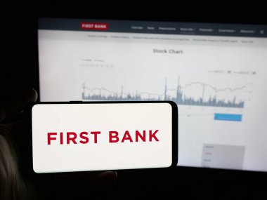 Stuttgart, Almanya - 12-18-2025: Finans şirketi First Bank 'ın (LocalFirstBank) logosuna sahip akıllı telefon web sitesinin önünde ekranda. Telefon ekranına odaklan.