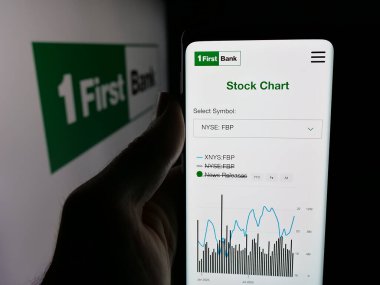 Stuttgart, Almanya - 12-18-2025: Finans şirketi First Bancorp 'un (FirstBank) web sitesi ile akıllı telefon sahibi kişi logonun önünde ekranda. Telefon ekranının merkezine odaklan.