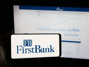 Stuttgart, Almanya - 12-18-2025: Web sitesi önünde ekranda ABD 'li FB Financial Corp (FirstBank) şirketinin logosuna sahip akıllı telefon sahibi kişi görülüyor. Telefon ekranına odaklan.