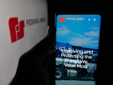 Stuttgart, Almanya - 12-18-2025: ABD 'li Federal Sinyal Şirketi' nin web sayfası olan akıllı telefon sahibi kişi logonun önünde ekranda. Telefon ekranının merkezine odaklan.