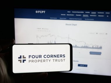 Stuttgart, Almanya - 12-18-2025: Web sitesinin önünde üzerinde Four Corners Property Trust Inc. (FCPT) logosu olan akıllı telefon sahibi kişi. Telefon ekranına odaklan.
