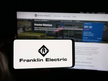 Stuttgart, Almanya - 12-18-2025: ABD 'li Franklin Electric Co. Inc. şirketinin logosunu elinde tutan kişi web sitesinin önünde ekranda. Telefon ekranına odaklan.