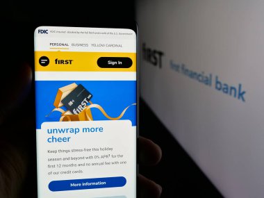 Stuttgart, Almanya - 12-18-2025: Logonun önünde First Financial Bancorp (Bankatfirst) şirketinin web sayfası olan akıllı telefonu elinde tutan kişi. Telefon ekranının merkezine odaklan.
