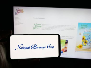 Stuttgart, Almanya - 12-18-2025: ABD 'li içecek şirketi National Beverage Corp' un logosunu elinde tutan kişi web sitesinin önünde ekranda. Telefon ekranına odaklan.