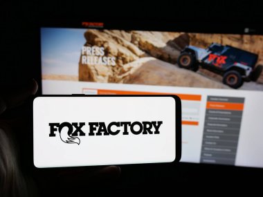 Stuttgart, Almanya - 12-18-2025: İnternet sitesinin önünde Fox Factory Holding Corp (RideFox) şirketinin logosuna sahip akıllı telefon sahibi kişi. Telefon ekranına odaklan.