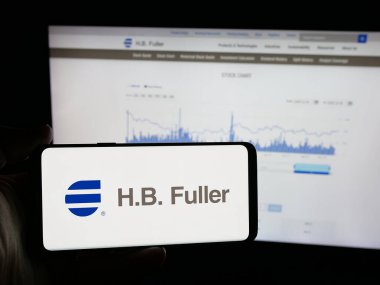 Stuttgart, Almanya - 12-19-2025: Amerikan yapıştırıcı şirketi H.B. 'nin logosuna sahip akıllı telefon sahibi kişi Fuller Şirketi web sitesinin önünde ekranda. Telefon ekranına odaklan.
