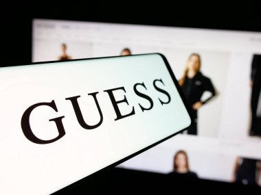 Stuttgart, Almanya - 12-19-2025: ABD 'li giyim şirketi Guess Inc.' in logosuna sahip akıllı telefon web sitesinin önünde ekranda. Telefon ekranının merkez soluna odaklan.