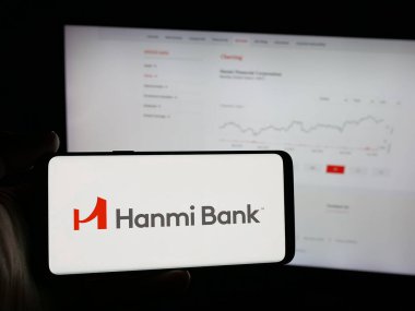 Stuttgart, Almanya - 01-15-2026: Bankacılık şirketi Hanmi Financial Corporation 'ın logosunu elinde tutan kişi web sitesinin önünde ekranda. Telefon ekranına odaklan.