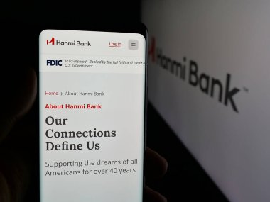 Stuttgart, Almanya - 01-15-2026: Bankacılık şirketi Hanmi Financial Corporation 'ın internet sayfası ile akıllı telefon sahibi kişi logo önünde ekranda. Telefon ekranının merkezine odaklan.
