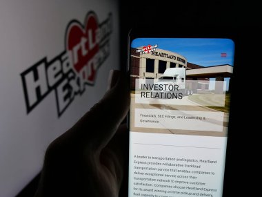 Stuttgart, Almanya - 01-19-2026: ABD 'li taşımacılık şirketi Heartland Express Inc.' in web sayfası ile akıllı telefon sahibi kişi logonun önünde ekranda. Telefon ekranının merkezine odaklan.