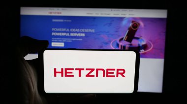 Stuttgart, Almanya - 01-19-2026: Veri merkezi şirketi Hetzner Online GmbH logosuna sahip cep telefonu web sayfası önünde ekranda. Telefon ekranına odaklan.