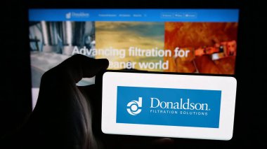 Stuttgart, Almanya - 01-22-2026: Web sayfasının önünde ekranda ABD filtreleme şirketi Donaldson Company Inc. 'in logosunun bulunduğu cep telefonu sahibi kişi. Telefon ekranına odaklan.