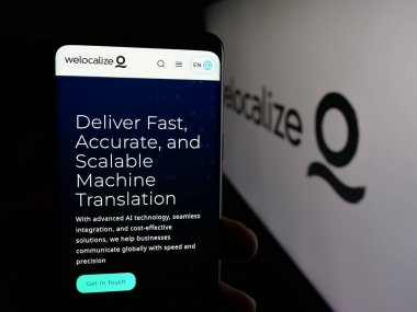 Stuttgart, Almanya - 01-22-2026: AI çeviri şirketi Welocalize Inc. 'in web sayfası ile cep telefonu tutan kişi logonun önünde ekranda. Telefon ekranının merkezine odaklan.