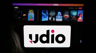Stuttgart, Almanya - 01-29-2026: Web sayfası önünde ekranda AI müzik jeneratörü şirketi Udio 'nun logosunun bulunduğu cep telefonu sahibi kişi. Telefon ekranına odaklan.