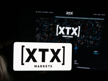 Stuttgart, Almanya - 01-30-2026: İngiliz ticaret şirketi XTX Markets Limited 'in logosuna sahip akıllı telefon sahibi kişi web sitesinin önünde ekranda görülüyor. Telefon ekranına odaklan.