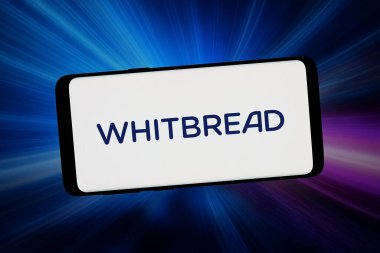 Stuttgart, Almanya - 02-12-2026: Bu resimde, İngiliz otel şirketi Whitbread plc 'in logosu bilgisayar ekranında soyut bir arkaplanda akıllı bir telefonla gösteriliyor.
