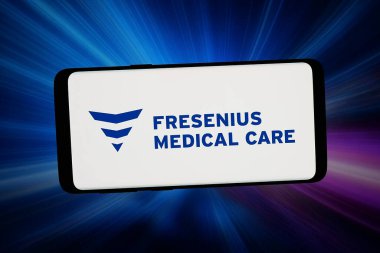Stuttgart, Almanya - 02-16-2026: Bu fotoğraf illüstrasyonunda, diyaliz şirketi Fresenius Medical Care 'in logosu bilgisayar ekranında soyut bir arkaplanda akıllı telefon önünde sergilenmektedir..