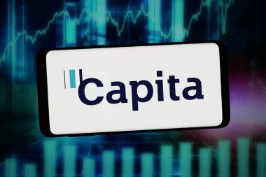 Stuttgart, Almanya - 02-19-2026: Bu fotoğraf illüstrasyonunda, İngiliz dış kaynak şirketi Capita plc 'nin logosu bilgisayar ekranında soyut bir arkaplanda akıllı telefon önünde sergilenmektedir..