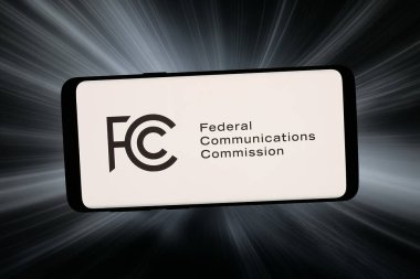 Stuttgart, Almanya - 02-20-2026: Bu fotoğraf illüstrasyonunda, Federal İletişim Komisyonu FCC 'nin logosu bilgisayar ekranında soyut bir arkaplan önünde akıllı bir telefonla gösteriliyor.