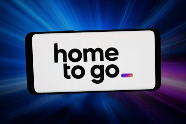 Stuttgart, Almanya - 02-27-2026: Bu fotoğraf illüstrasyonunda, Alman seyahat şirketi HomeToGo GmbH 'nin logosu bilgisayar ekranında soyut bir arkaplanda akıllı telefon önünde sergilenmektedir..