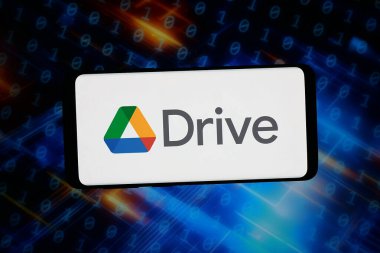 Stuttgart, Almanya - 03-02-2026: Bu fotoğraf illüstrasyonunda, dosya sunucu platformu Google Drive 'ın logosu bilgisayar ekranındaki soyut arkaplan önünde bir akıllı telefonda gösteriliyor.
